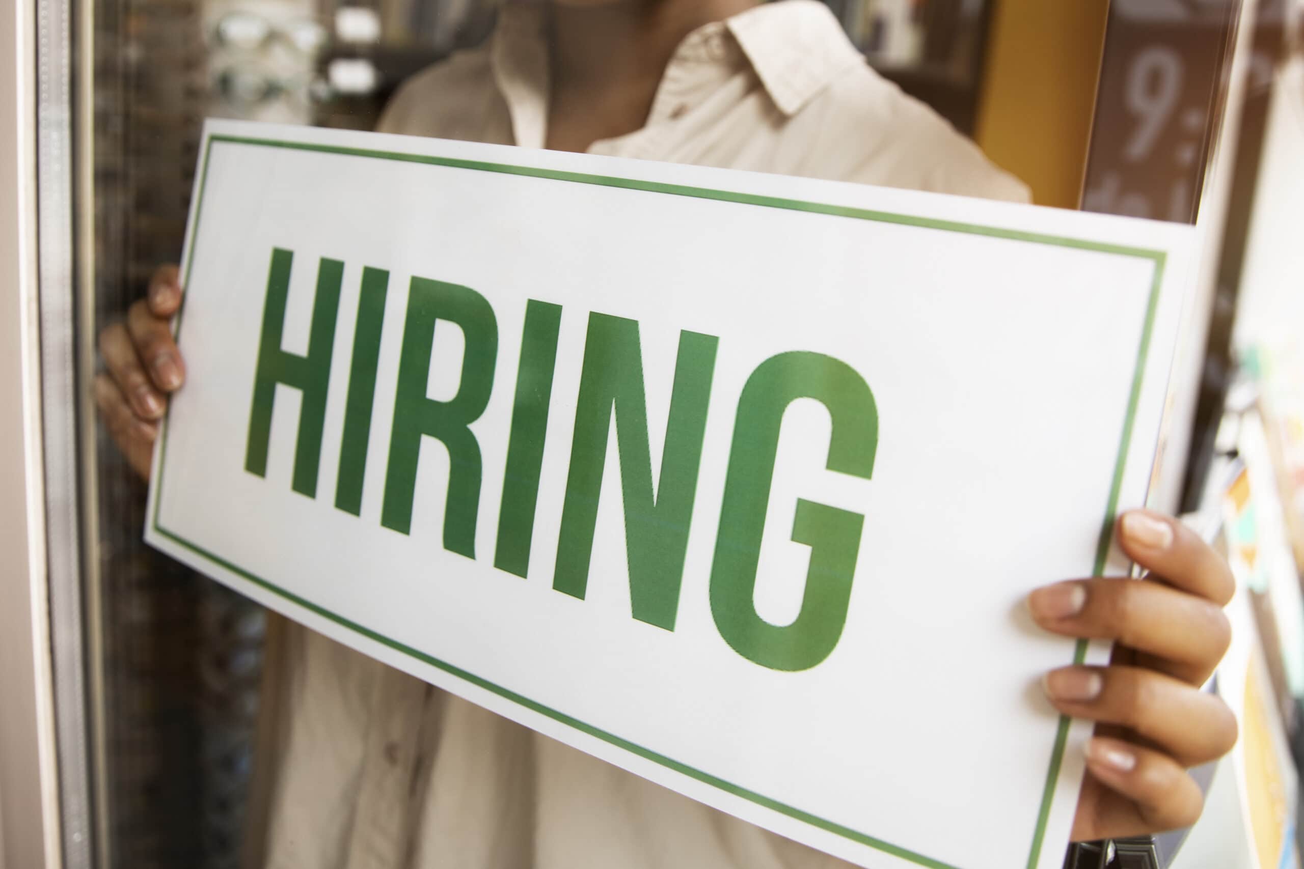Vacancies 82 person with hiring sign by window scaled